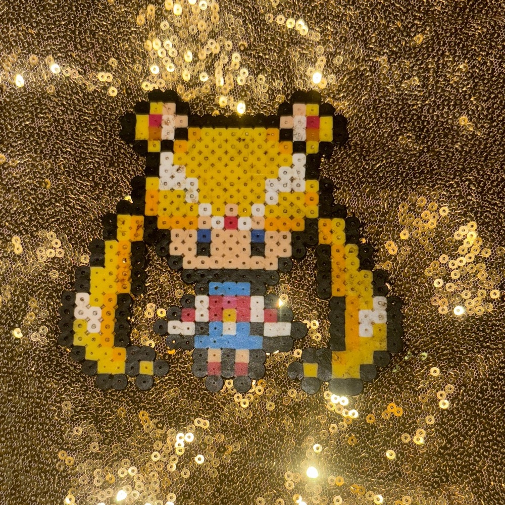 Pixel Art Beaded Character on Gold Sequin Background